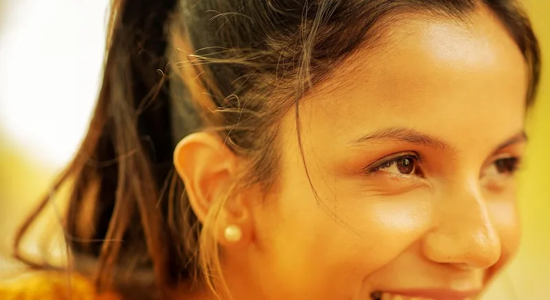 A woman smiles over a white cup of coffee